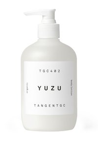 Bottiglia opaca bianca con pompa, etichettata "YUZU", contiene lozione per il corpo biologica. Design semplice con testo nero e una texture liscia.