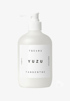 Weiße, opake Flasche mit einem Pumpkopf, beschriftet mit "YUZU", enthält organische Körperlotion. Einfaches Design mit schwarzem Text und glatter Textur.