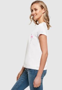 White cotton T-shirt with short sleeves featuring a pink flamingo graphic. Casual fit with a rounded neckline and soft textile texture.