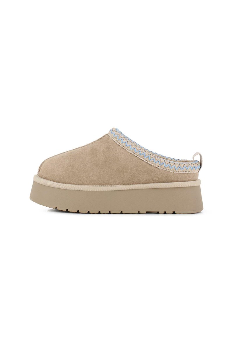 Zapato de ante beige tipo slip-on con un borde tejido en azul claro texturizado, suela de plataforma elevada y diseño de punta redonda.