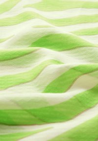 Grøn- og hvidmønstret stof med bølgede striber, der har en tekstureret overflade og subtile brune accenter spredt ud.