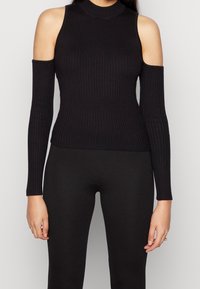 Czarny rypsowany top z długim rękawem, wycięciami na ramionach i wysokim kołnierzem. Dopasowany fason, gładka tekstura oraz subtelna elastyczność.