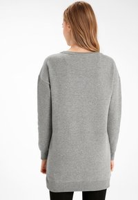 Sweat-shirt gris à coupe décontractée, manches longues, encolure arrondie et poignets côtelés. Confectionné dans un tissu doux, idéal pour une tenue décontractée.