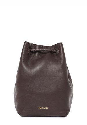 Brown leather bucket bag with a drawstring closure; smooth texture and a subtle sheen; features a gold logo accent on the front.