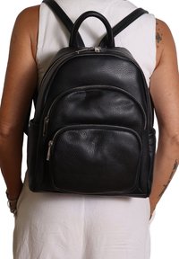 Zaino in pelle nera con finitura testurizzata, dotato di un compartimento principale, due tasche anteriori con zip e spallacci imbottiti.