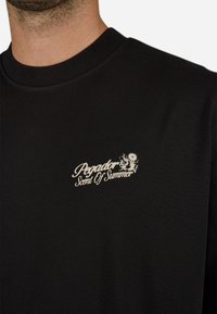 Sort bomulds T-shirt med rund halsudskæring og et hvidt trykt logo med teksten "Pegador Scent Of Summer" på venstre side.