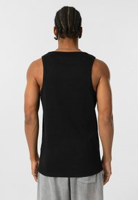 Zwarte geribbelde tanktop met een ronde halslijn en schouderbanden, met een rechte zoom en een relaxte pasvorm.