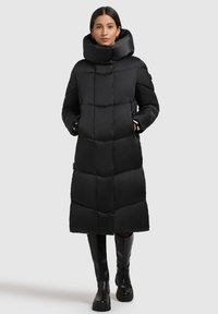 Lang sort pufferjakke med kviltet design, høj krave og sidelommer. Lavet af glat stof, har en lige silhuet og en knælang længde.