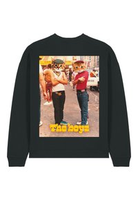 Melna sporta krekls ar grafisku attēlu, kurā attēloti divi kaķi cilvēku apģērbā, fona ir krāsaina pilsētas ainava, ar uzrakstu "Zēni".