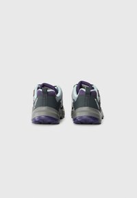 Pair of gray and purple athletic shoes seen from the back with pull tabs and textured soles on a white background.
