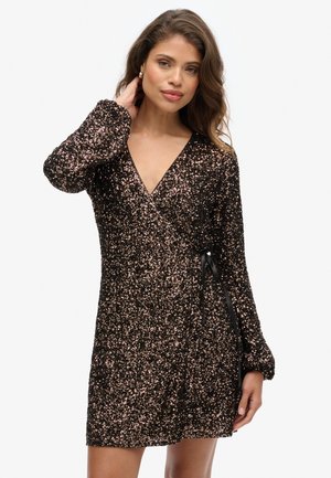 Robe noire enveloppante avec des sequins rose doré, manches longues, décolleté en V profond et détail de taille nouée. Texture douce, longueur courte et finition scintillante.