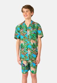 Camisa de manga corta con botones y pantalones cortos a juego en un patrón de paisaje pixelado colorido que presenta tonos verdes, azules y marrones.