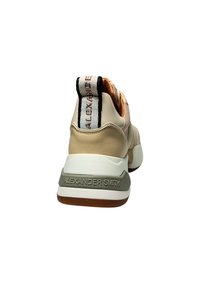 Beige Sneaker mit strukturiertem Mesh-Obermaterial, glatten Lederakzenten, gepolstertem Schaftrand und geprägtem Branding auf der Ferse in kontrastierenden Farben.