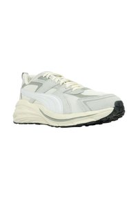 Zapatilla deportiva gris claro con paneles de malla blanca, acentos de ante texturizado, punta redondeada, suela beige y banda de rodadura de goma negra.