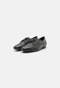 Black leather dress shoes with a sleek design, pointed toe, and flat sole. Features laces and smooth surface texture.