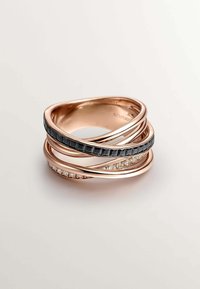 Tres anillos entrelazados en oro rosa, que presentan una banda negra con acentos en forma de cuadrado y uno con pequeñas piedras transparentes, mostrando diferentes texturas.