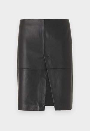 Jupe noire en cuir longueur genou avec une fente avant et des détails de couture horizontale et verticale apparents.