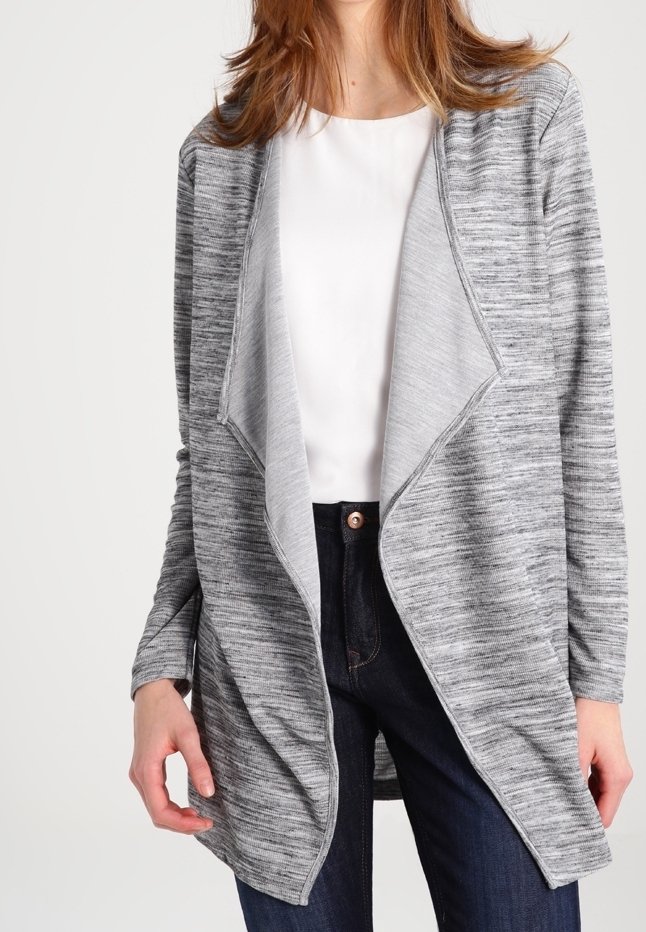 Cardigan grigio a maglia con design a cascata, maniche lunghe e tessuto morbido, indossato sopra una maglietta bianca e jeans scuri.
