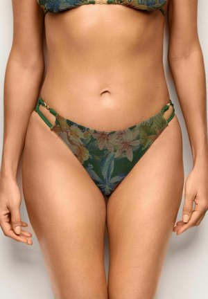 Kobieta w majtkach bikini z wysokim stanem w zielony, niebieski i pomarańczowy wzór kwiatowy z podwójnymi bocznymi paskami na neutralnym tle.