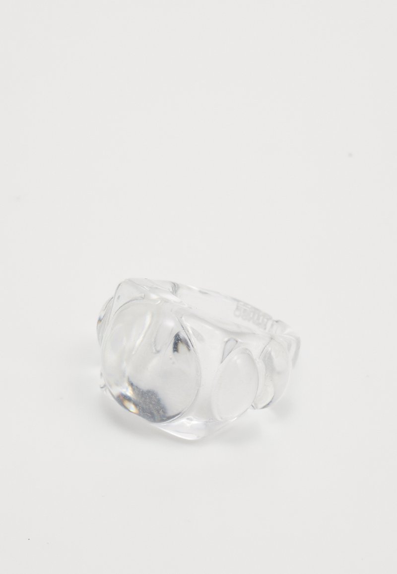 Bague en résine transparente présentant un design arrondi avec des accents lisses et bulbés. La surface est brillante avec des reflets de lumière, ajoutant de la profondeur.