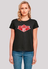 Black cotton T-shirt with short sleeves featuring a bold red "BEASTIE BOYS" logo in a diamond shape on the front. Regular fit.