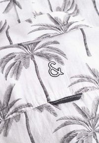 Camicetta a maniche corte in tessuto bianco con stampa di palme nere. Presenta un logo ricamato "&" e un accento nero a contrasto sull'orlo.