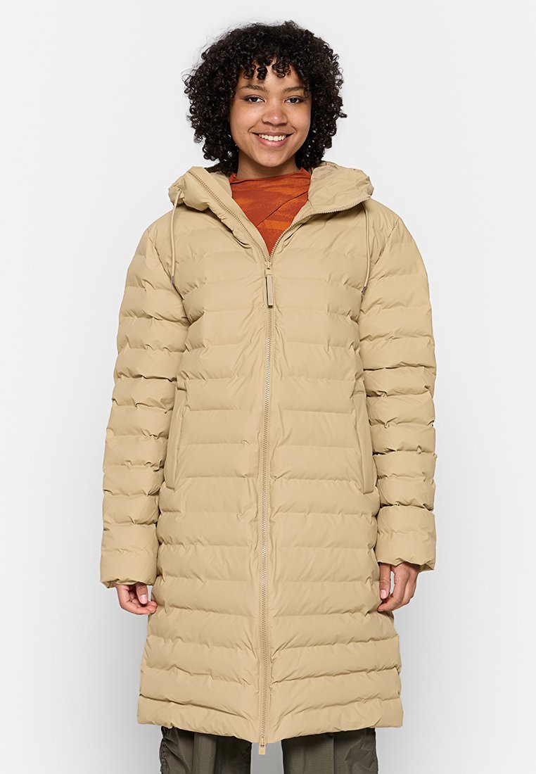 Manteau long en doudoune beige, avec des sections matelassées horizontales, une capuche et une fermeture éclair à l'avant. Texture lisse avec un design léger.