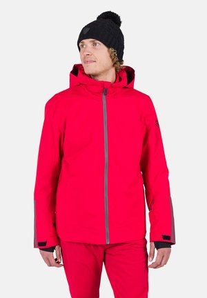 Giacca impermeabile fucsia con zip e dettagli grigi, dotata di cappuccio e polsini regolabili. Abbinata a pantaloni rosa coordinati.