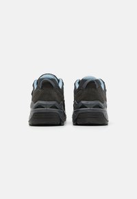 Sneakers in suede nero e mesh con suola in gomma testurizzata, caratterizzati da accenti blu chiaro sul colletto e sulla linguetta.
