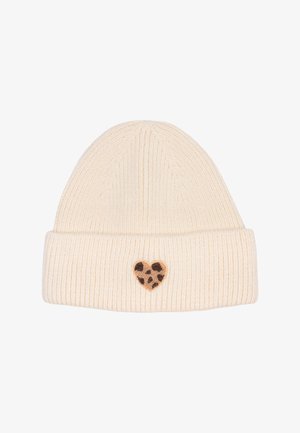 Cream-colored knit beanie with a ribbed design. Features a small, brown spotted heart patch on the front. Soft texture.