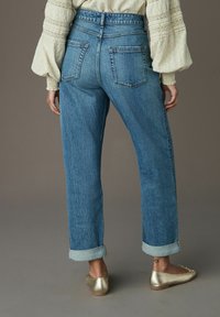 Högmidjade jeans i ljusblått med uppvikta benslut, två bakfickor och en strukturerad yta.