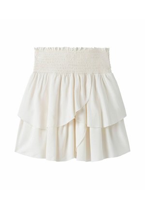 Gonna bianca a strati con vita elastica arricciata e strati di tessuto asimmetrici e fluidi.