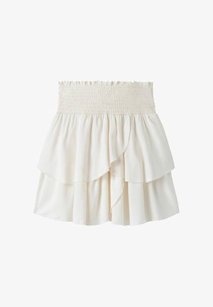 Jupe blanche à plusieurs couches avec une ceinture élastique smockée et des couches de tissu fluides et asymétriques.