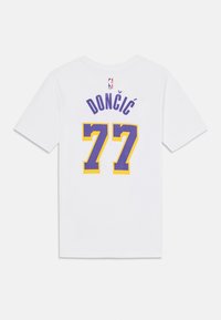 Vit kortärmad T-shirt med "DONČIĆ" i lila bokstäver och siffran "77" i gult och lila. NBA-logotyp på kragen.