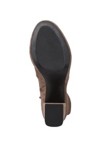 Bottine en suède marron avec une semelle en caoutchouc noir, featuring des rainures horizontales pour l'adhérence et un design à talon carré.