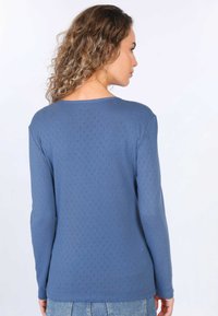 Blue long-sleeve top with a textured pattern, rounded neckline, and fitted design. Material appears soft and comfortable.