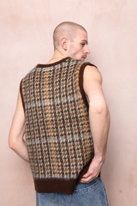 Megztas be rankovių liemenė su languotu raštu rudomis, oranžinėmis ir mėlynomis atspalviais; turi riebų rudą apykaklę ir apatinę dalį.