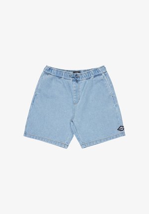 Shorts en velours côtelé bleu clair avec un ourlet retroussé, assortis à des baskets noires et des chaussettes foncées. Le tissu présente des côtes verticales visibles.