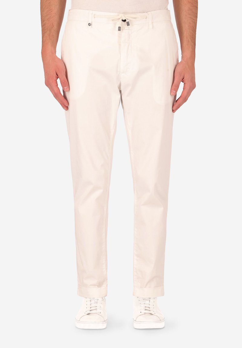 Chinos color beige chiaro con cintura regolabile, tasche laterali e design con gamba affusolata. Realizzati in un tessuto morbido, abbinati a sneakers bianche.