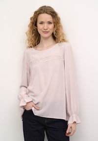 Lyserød bluse med rund halsudskæring, blonde detaljer over brystet og indsamlede manchetter. Blødt stof med en afslappet pasform.