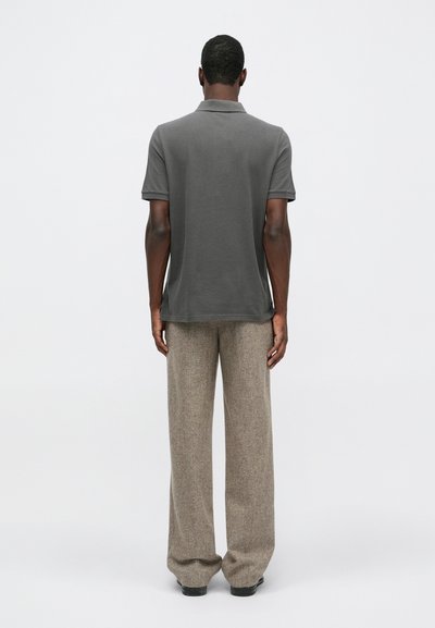 Šedý polo tričko s krátkými rukávy, spárované se světlými hnědými texturovanými kalhotami typu široké nohavice. Minimalistický design, jednobarevné, neformální vzhled.