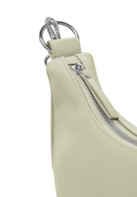 Borsa in pelle verde chiaro con una texture liscia, dotata di una cerniera argento e dettagli in metallo circolare. Vista ravvicinata dei dettagli della borsa.