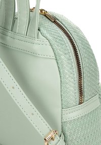 Bolso de mano en verde menta con un diseño texturizado de tejido, acentos de cuero suave, herrajes dorados en el cierre y dos asas superiores.