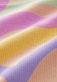 Färggabande tyg med mjuk, ribbad textur och vågiga mönster i rosa, lila, gult och blekgröna toner.