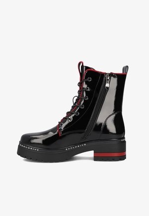 Czarne lakierowane botki za kostkę z czerwonymi akcentami, z przodem sznurowanym, bocznym zamkiem błyskawicznym oraz żebrowaną podeszwą platformową. Logo "EXCLUSIVE" na boku.