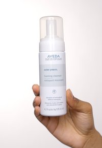Aveda Outer Peace detergente schiumogeno in una bottiglia bianca con dispenser. Contiene 4,2 fl oz (125 ml) e ha un design minimalista.