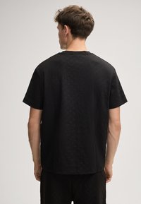 Schwarzes Kurzarmhemd mit strukturiertem Muster, Rundhalsausschnitt und lockerer Passform, aus einem glatten, atmungsaktiven Stoff gefertigt.