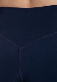 Leggings a vita alta blu navy realizzati in un materiale liscio e elastico, con un design senza cuciture e cuciture a contrasto sottili.