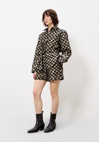 Set van een jas en short met luipaardprint, gemaakt van zachte stof. De jas heeft een kraag, lange mouwen en een ceintuur in de taille; gecombineerd met zwarte enkelboots.