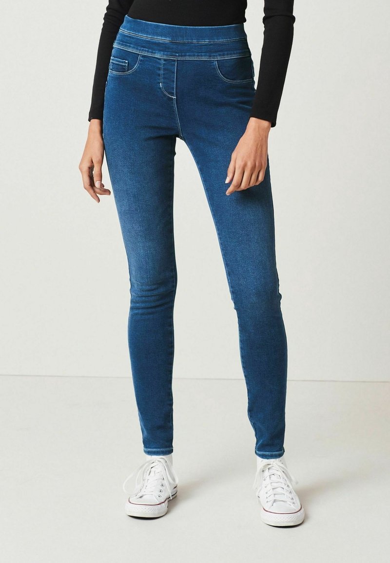 Modré džíny s vysokým pasem, s předními kapsami a slim fit střihem. Vyrobené z denimu s hladkou texturou. Nositelské s bílými teniskami.